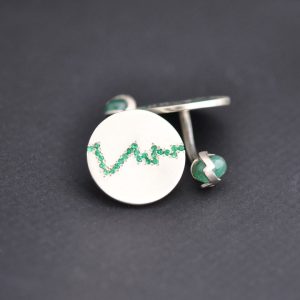 White gold cufflinks studded with emeralds, the 20th anniversary stone, in a pattern representing the profile of a mountain top.