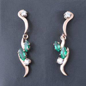 Delicate gold earrings set with emeralds and diamond that move and catch the light.